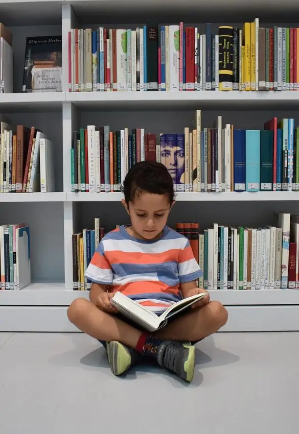Ein Junge liest vor einem Bücherregal